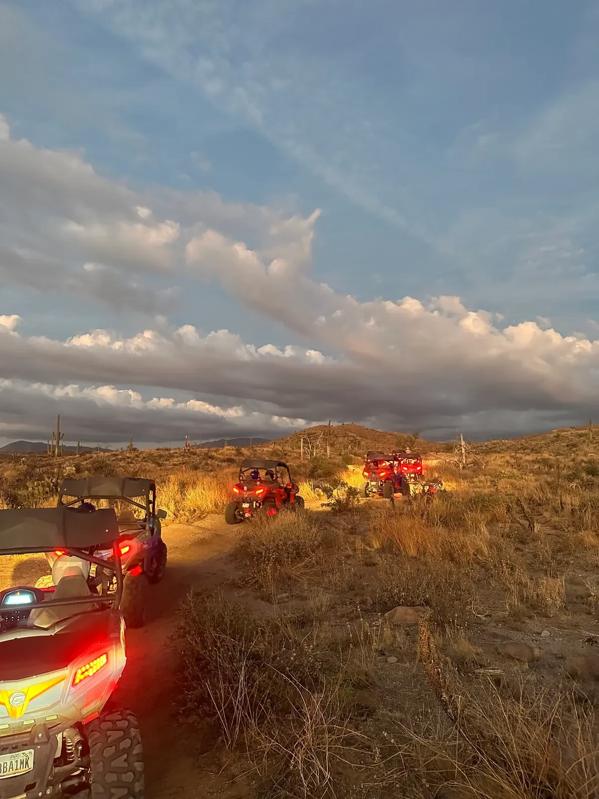 Sand buggies driving into dusk under a dramatic Sonoran Desert sky